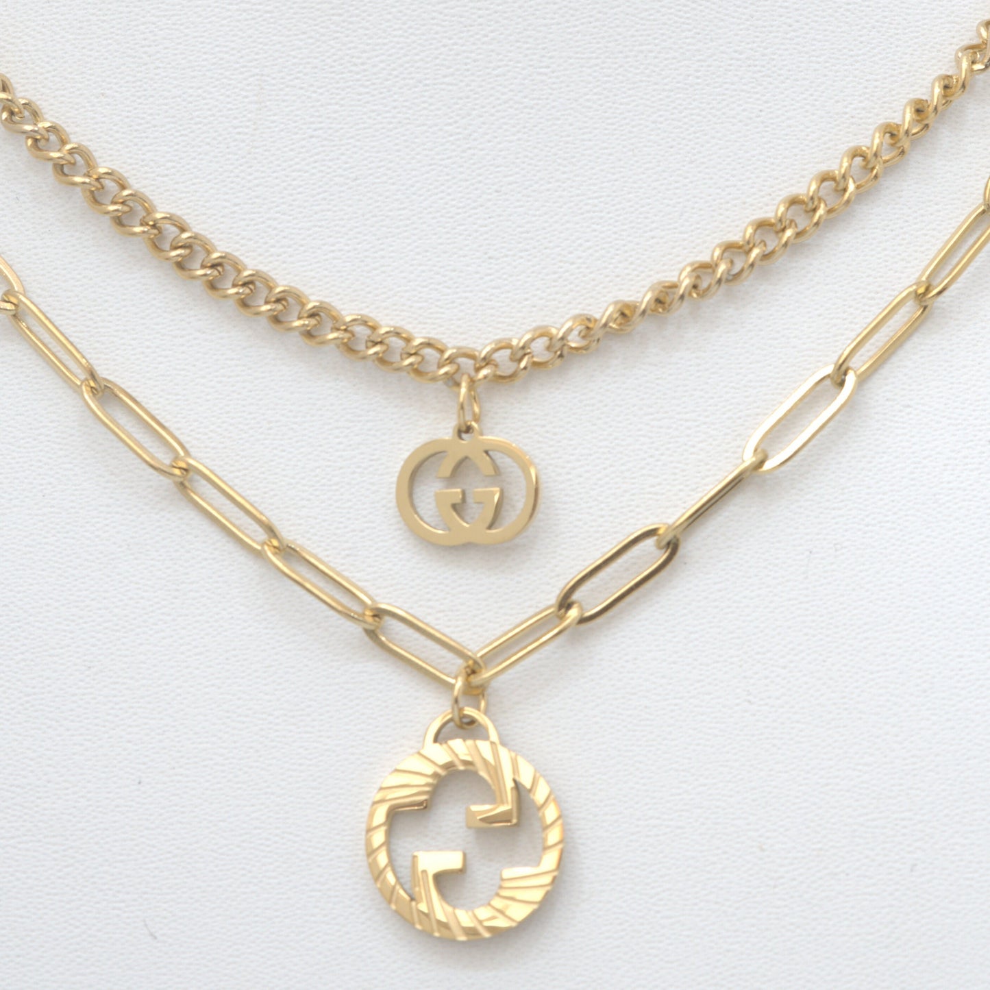 Gold necklaces with Gucci logo pendants on a light gray background