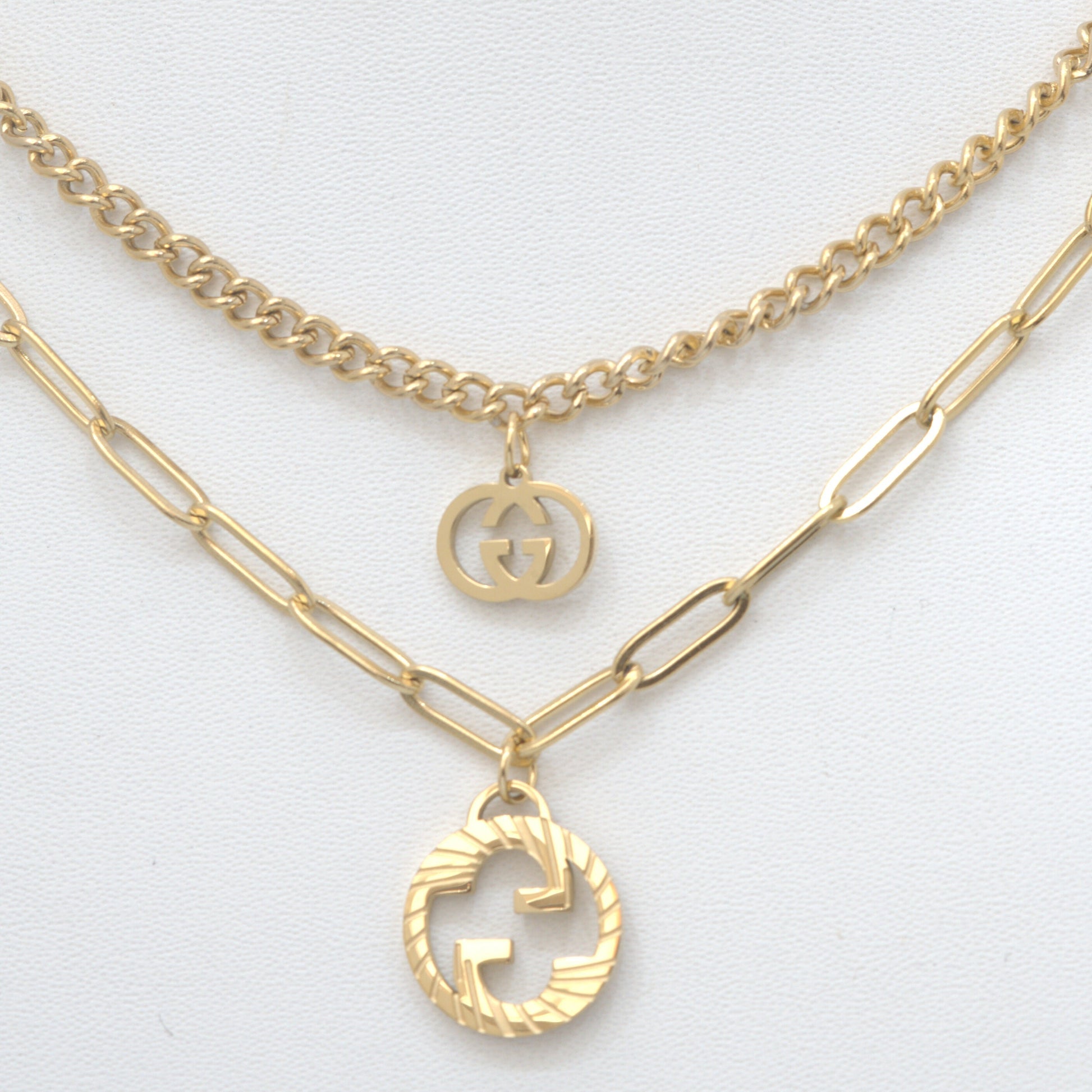 Gold necklaces with Gucci logo pendants on a light gray background